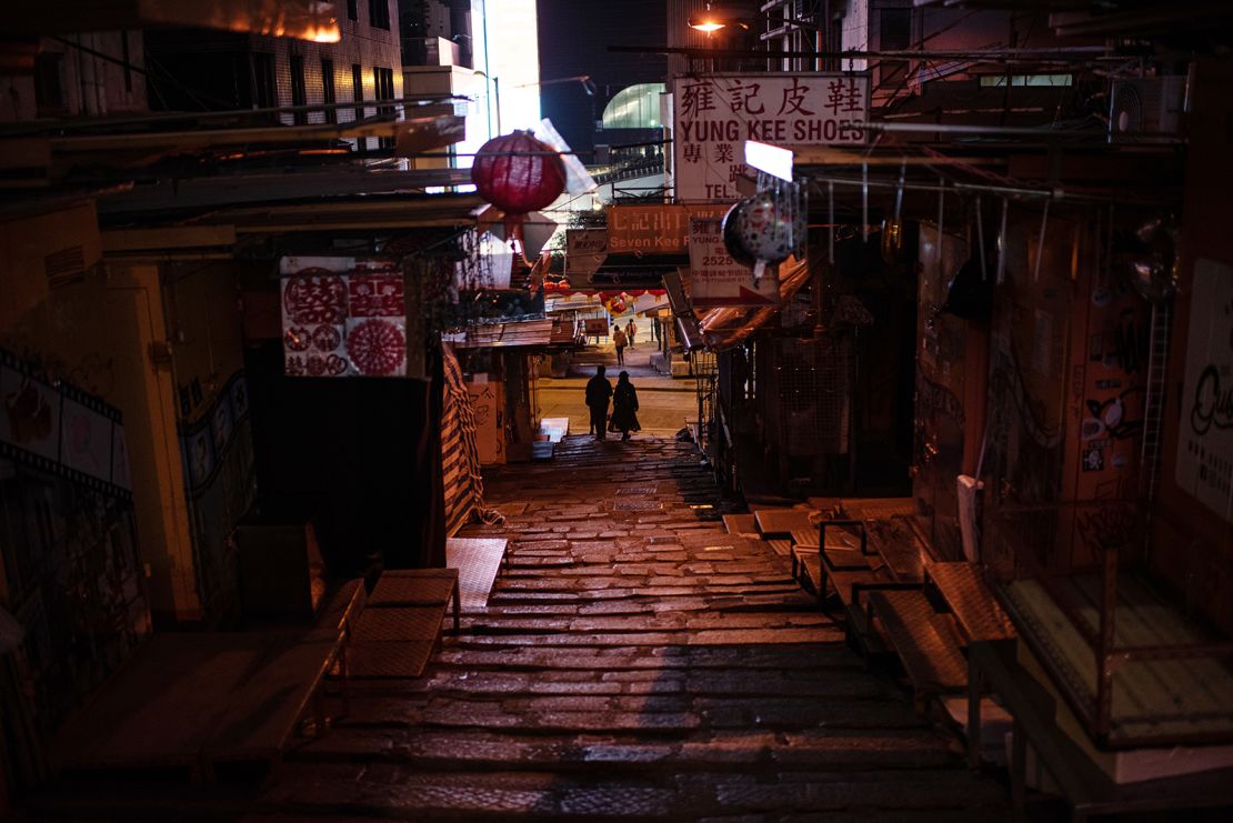 Pedestrians along a near empty street at night in Hong Kong, February 24, 2022.
