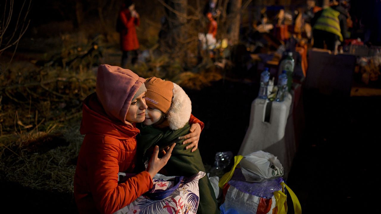 A woman holds a young girl as they cross into Romania at the Siret border crossing on Friday.