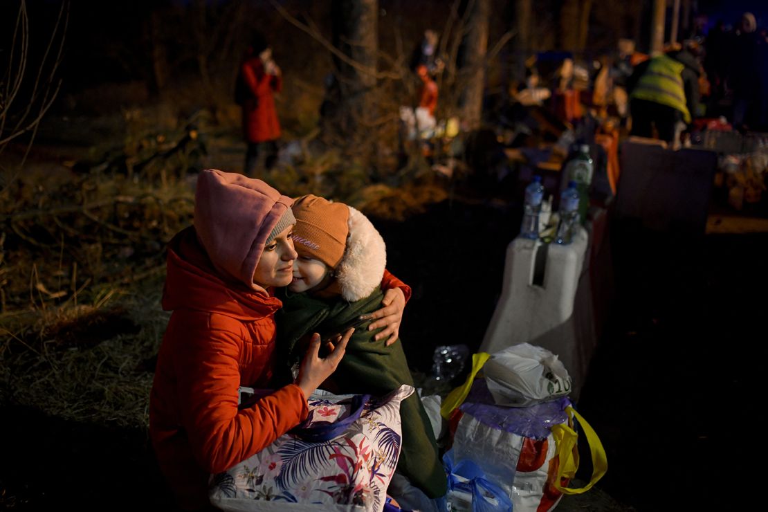 A woman holds a young girl as they cross into Romania at the Siret border crossing on Friday.