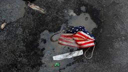 A protective face mask imprinted with the U.S. flag lays on the ground, amid the coronavirus disease (COVID-19) pandemic, as a person walks by outside Pennsylvania Station in New York City, U.S., October 5, 2021. REUTERS/Shannon Stapleton     TPX IMAGES OF THE DAY