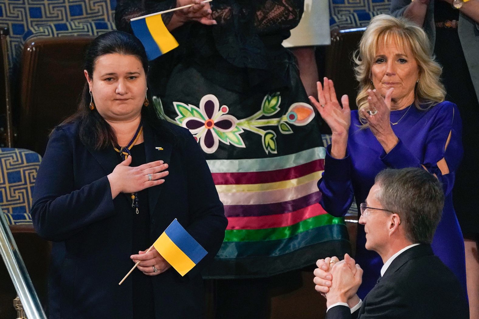 Oksana Markarova, the Ukrainian ambassador to the United States, is applauded while standing next to first lady Jill Biden. "She's bright, she's strong, she's resolved," the President said as <a href="index.php?page=&url=https%3A%2F%2Fwww.cnn.com%2Fpolitics%2Flive-news%2Fbiden-state-of-the-union-2022%2Fh_d0cfc605feb5b2f5687c2b6ae1a55a73" target="_blank">he recognized her in his speech.</a> "Yes. We the United States of America stand with the Ukrainian people."