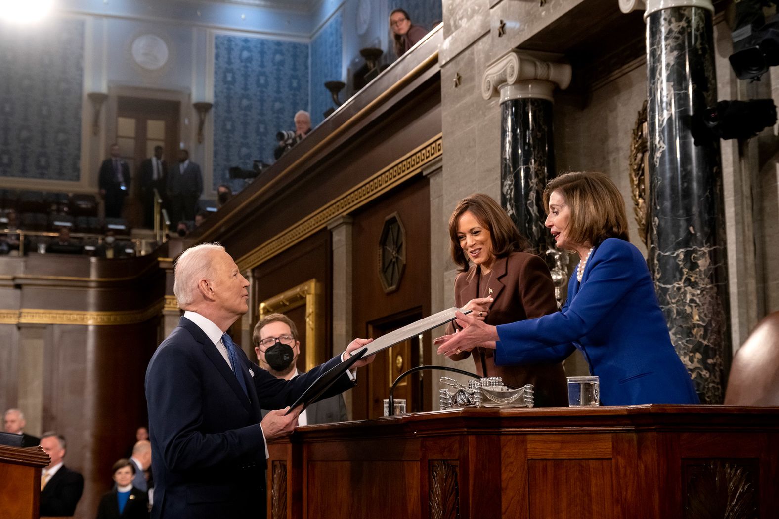 Biden presents copies of his speech to Harris and Pelosi.