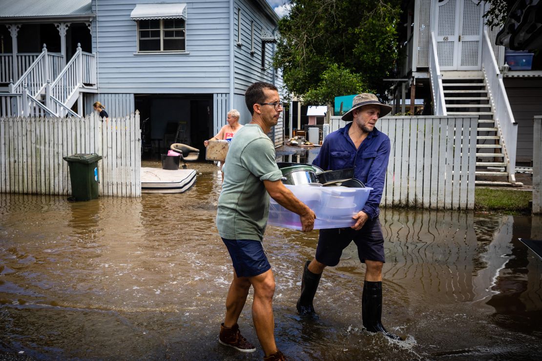 Residents carry belongings as they clean their homes in the flood-damaged suburb of Newmarket in Brisbane on March 1, 2022. 