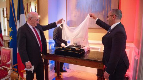 French Ambassador to the US Philippe Etienne (L) and Steve K. Francis, Acting Executive Associate Director for Homeland Security Investigations (HSI), unveil artifacts during a ceremony marking the restitution of cultural property from the US to France at the ambassador's residence in Washington, DC, on March 2, 2022. - The items include five gold ingots from the Prince de Conty, which sank near the Breton coast in 1746, a gold coin from the third century discovered in 1985 of Corsica's Gulf of Lava, and a skull from the Paris catacombs. (Photo by Nicholas Kamm / AFP) (Photo by NICHOLAS KAMM/AFP via Getty Images)