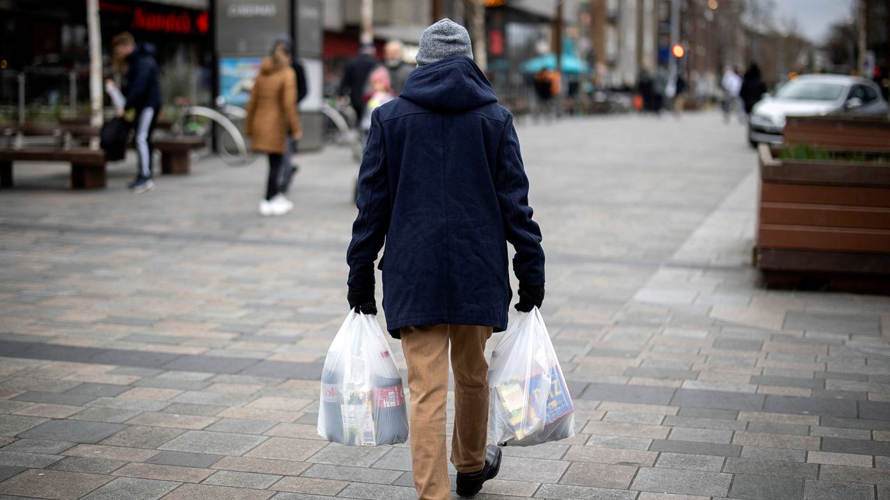 A shopper carries his purchases in Walthamstow, east London, on February 13.