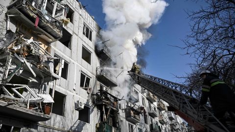Firefighters work on a fire on a building after bombings on the eastern Ukraine town of Chuguiv on February 24, 2022.