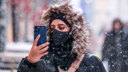 A woman takes pictures during a snowfall, on January 5, 2022, the Annette cyclone will bring 20% of the average monthly amount of precipitation. 