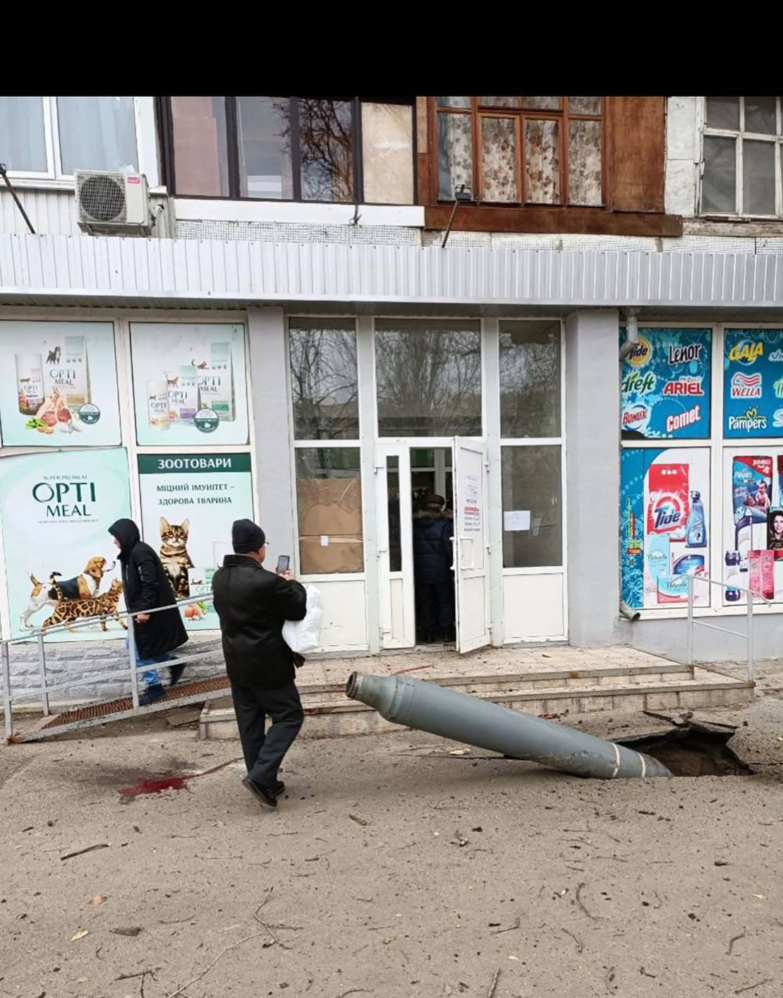 A missile is seen lodged in the ground outside a small grocery store in Kharkiv on Monday.