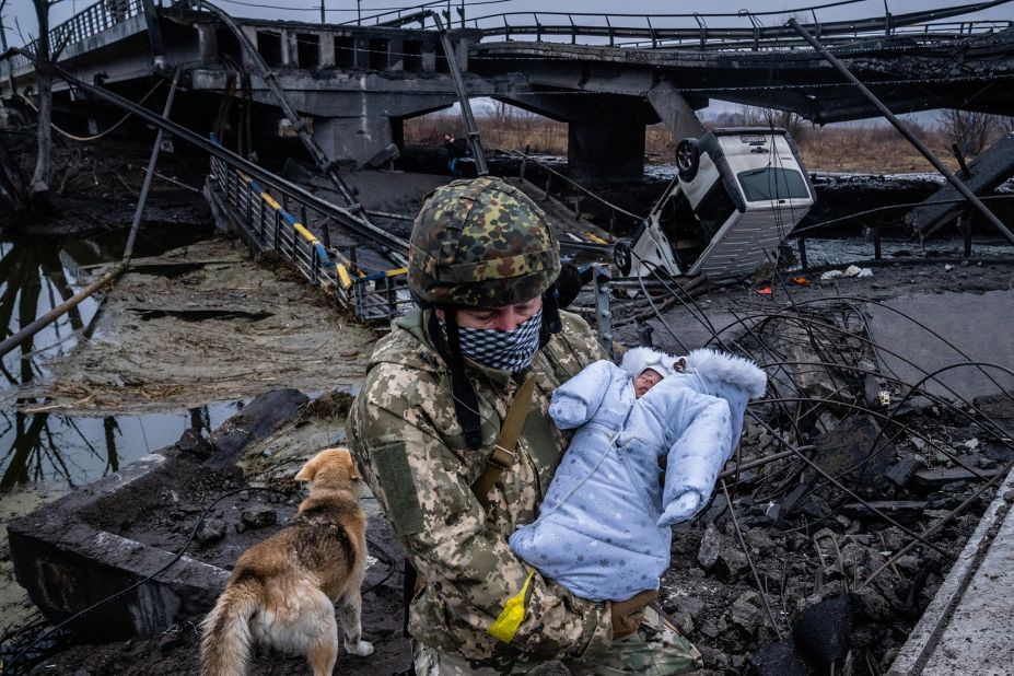 A Ukrainian soldier carries a baby across a destroyed bridge on the outskirts of Kyiv on March 3.