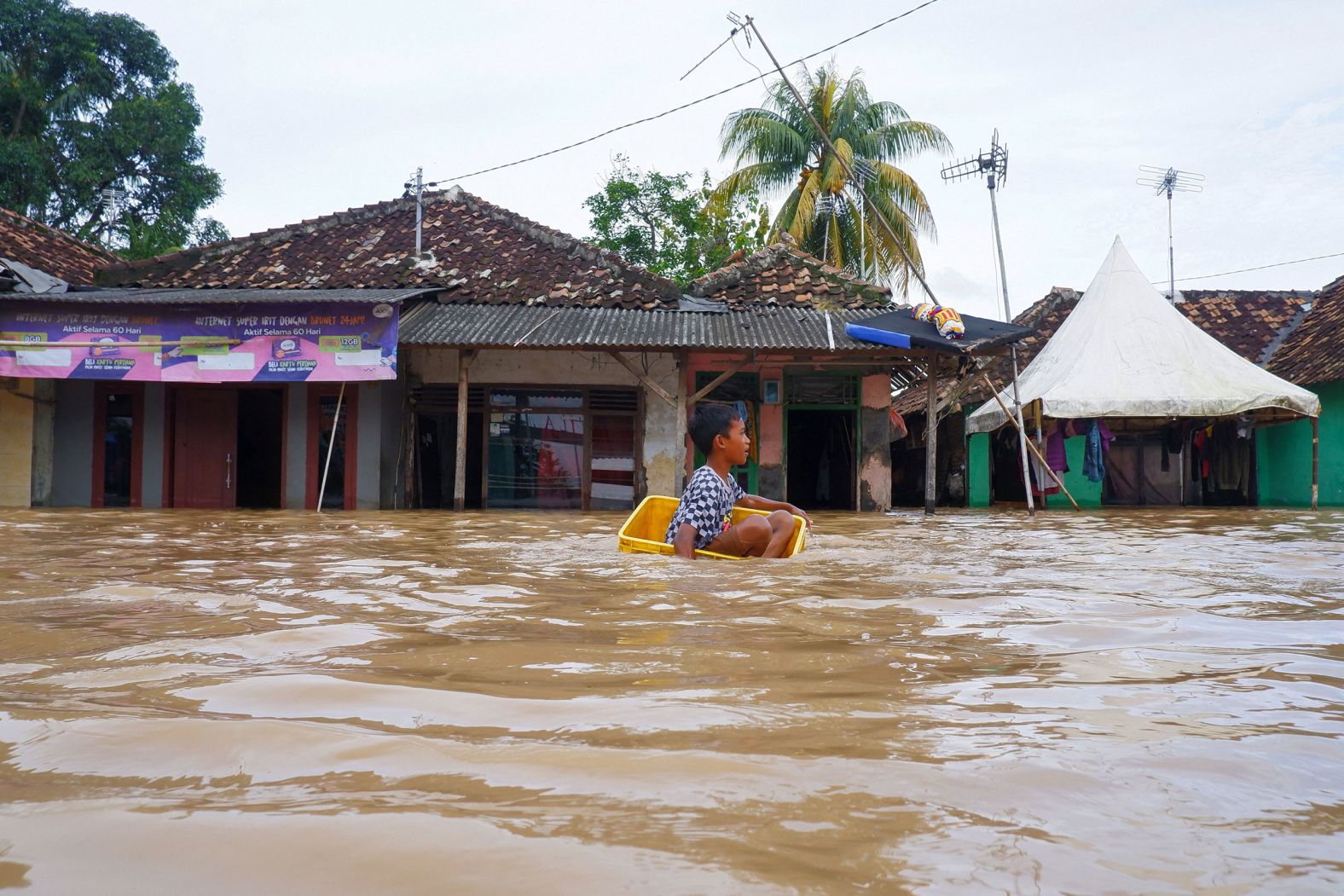 A boy uses a box to wade through floodwaters in Serang, Indonesia, on Tuesday, March 1. The flooding in Serang was caused by heavy rainfall.