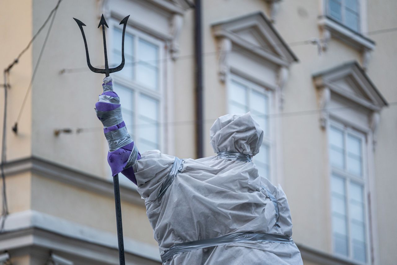 A statue of Roman god Neptune stands covered in protective plastic in Lviv's Market Square.