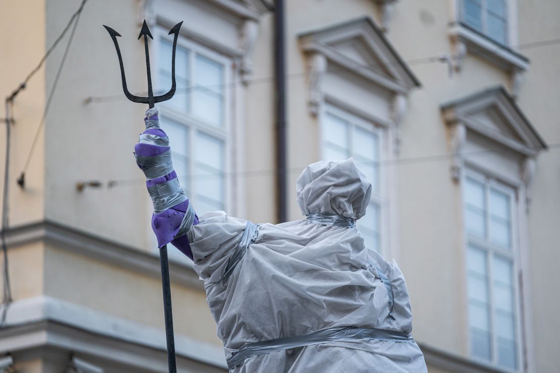 A statue of Roman god Neptune stands covered in protective plastic in Lviv's Market Square.