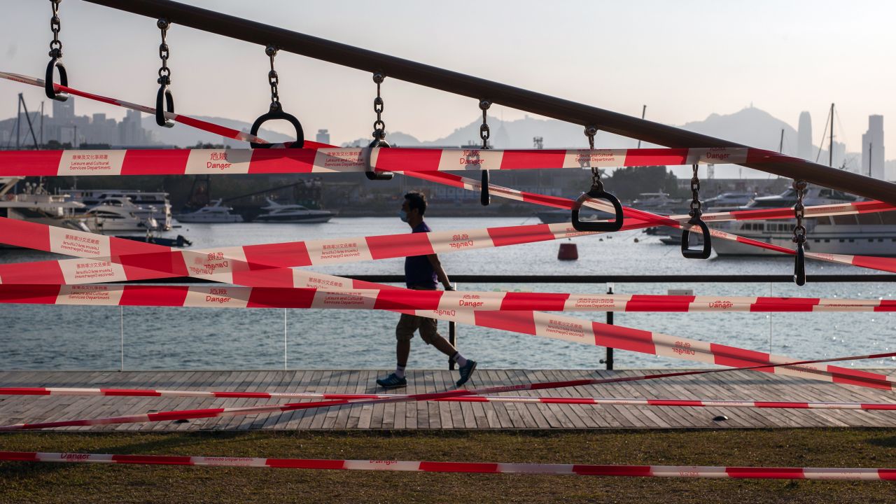 A pedestrian passes barrier tape cordoning off a gym facility, closed due to Covid-19 restrictions, at the Kwun Tong Promenade in Hong Kong on March 3, 2022. 