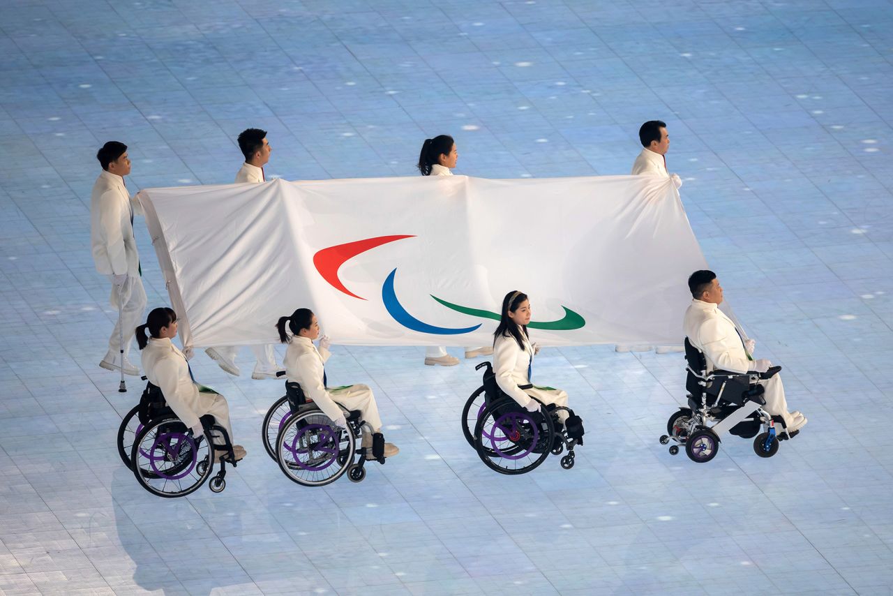 The flag of the Paralympic Committee is carried through the stadium.