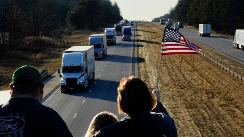 People hold a flag on an overpass in Brazil, Indiana on March 1, in support of a truck convoy bound for Washington, DC.