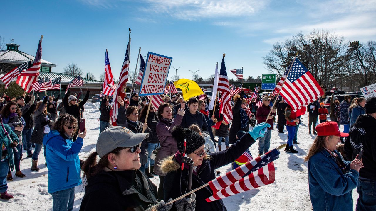 People wave flags and signs at the kickoff rally for the northeast convoy to DC at an I95 service area in Kennebunkport, Maine, March 2, 2022. 