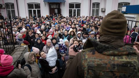 A member of the Ukrainian military gives instructions to women and children  boarding an evacuation train in Irpin, Ukraine.