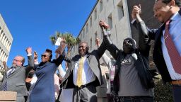 The family and attorneys of Ahmaud Arbery raise their arms in victory outside the federal courthouse in Brunswick, Georgia, after all three men involved in his killing were found guilty of hate crimes, February 22, 2022.