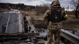 A Ukrainian serviceman looks at a civilian crossing a blown up bridge in a village, east of the town of Brovary on March 6.
