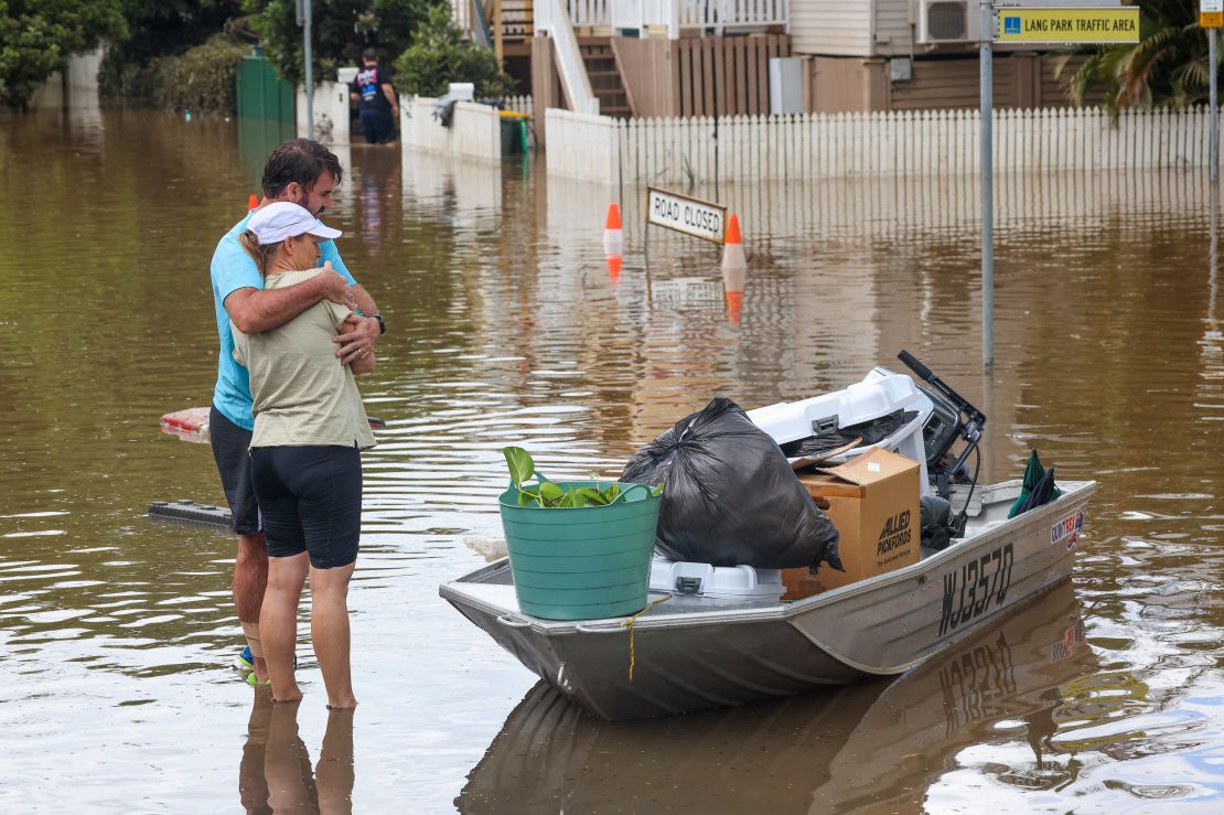 People hug after moving their belongings to a boat from a flooded home at Auchenflower on March 3, 2022.