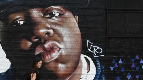 A woman passes by Brazilian artist Sipros' mural of the rapper Biggie Smalls, featured on a wall in the Bushwick section of Brooklyn, New York, on June 6, 2019.