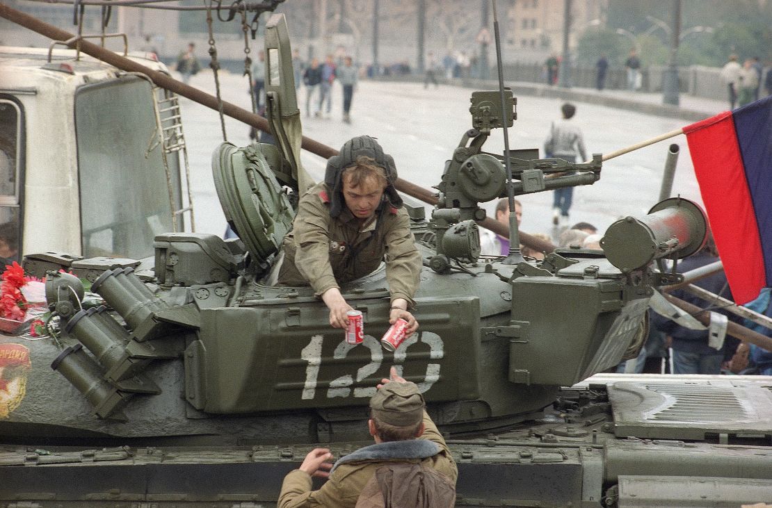 A soldier gives two cans of Coca-Cola to a tank driver near the Russian Federation building in Moscow, August 21, 1991.