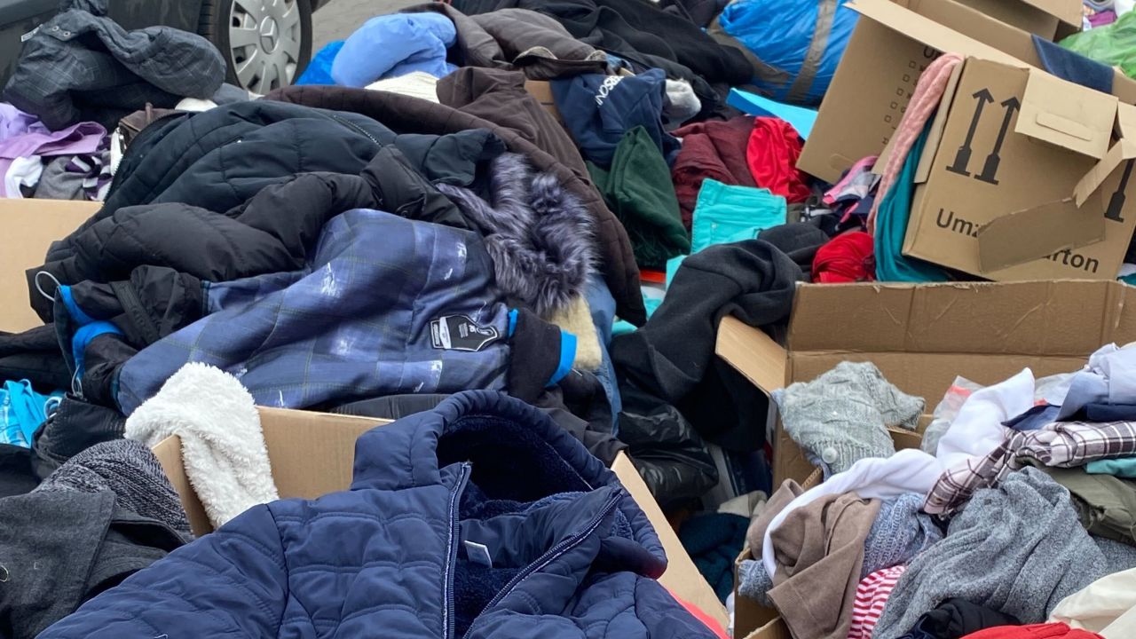 Small mountains of clothing, shoes, jackets and outerwear fill cardboard boxes just outside of the Przemyśl train station at a refugee relocation center.