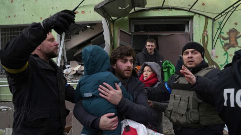 A man carries his child away from the damaged maternity  hospital in Mariupol on Wednesday.