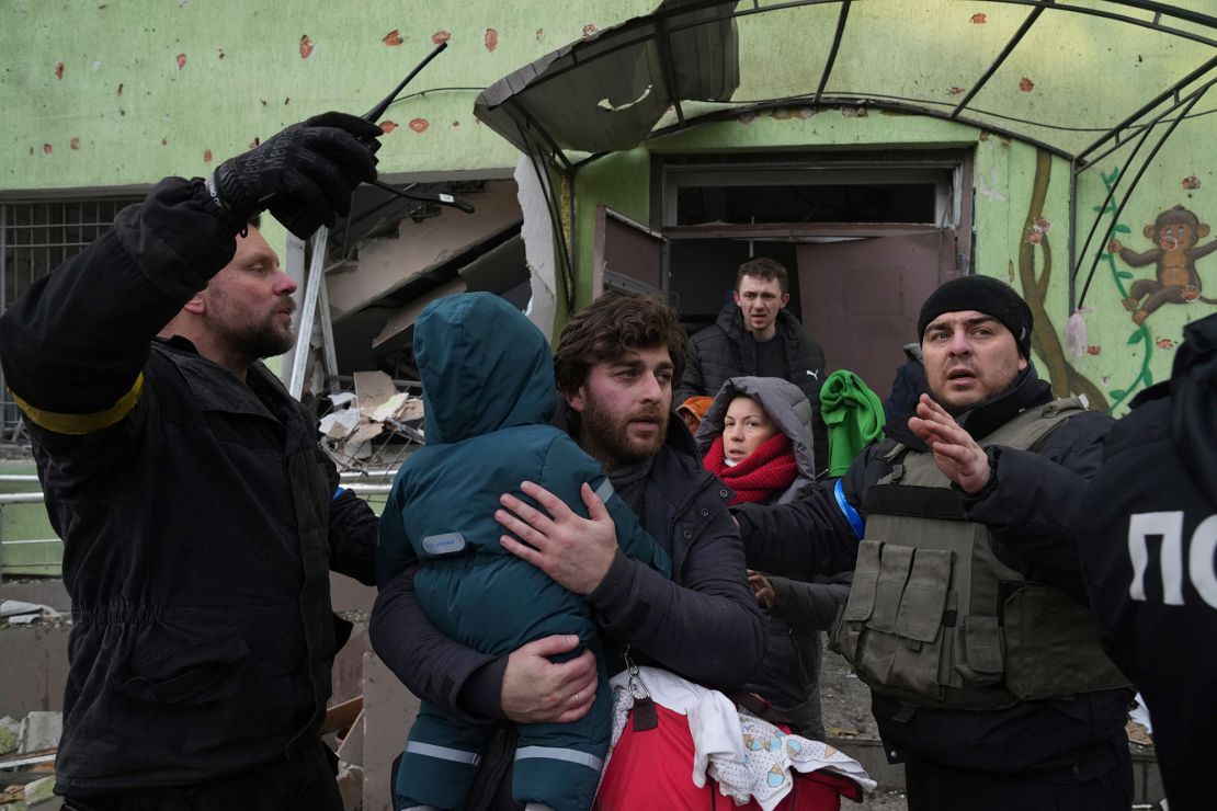 A man carries his child away from the damaged maternity  hospital in Mariupol on Wednesday.