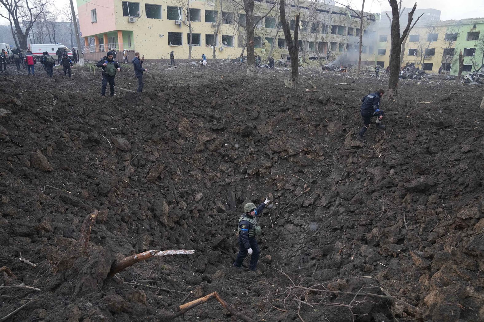 Ukrainian soldiers and emergency employees work at the site of the shelling.