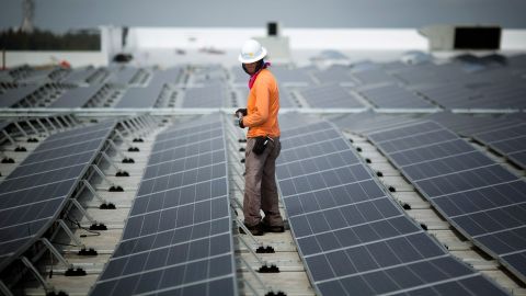 Un trabajador camina entre los paneles solares instalados en un techo de IKEA en Miami en 2014. Desde febrero, IKEA ha instalado energía solar en el 90 % de sus ubicaciones en EE. UU.
