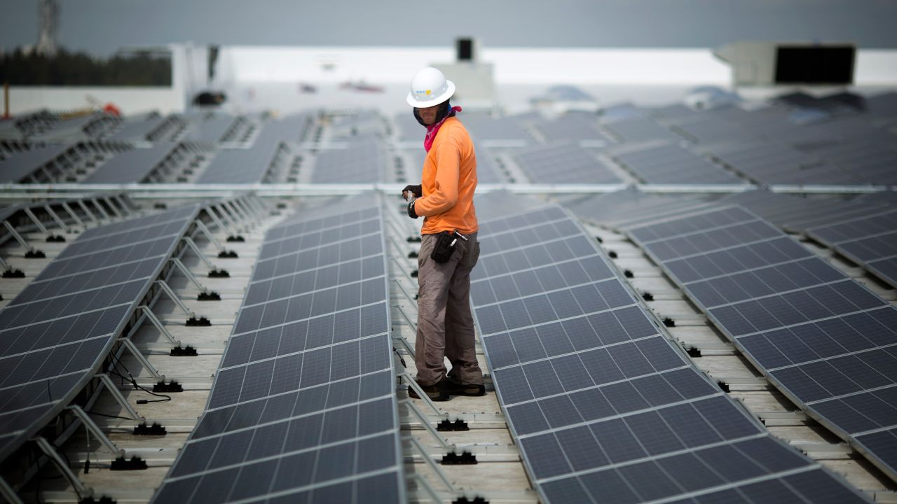 عامل يسير بين الألواح الشمسية التي تم تركيبها على سطح ايكيا في ميامي في عام 2014. اعتبارًا من فبراير ، قامت ايكيا بتركيب الطاقة الشمسية في 90٪ من مواقعها في الولايات المتحدة.