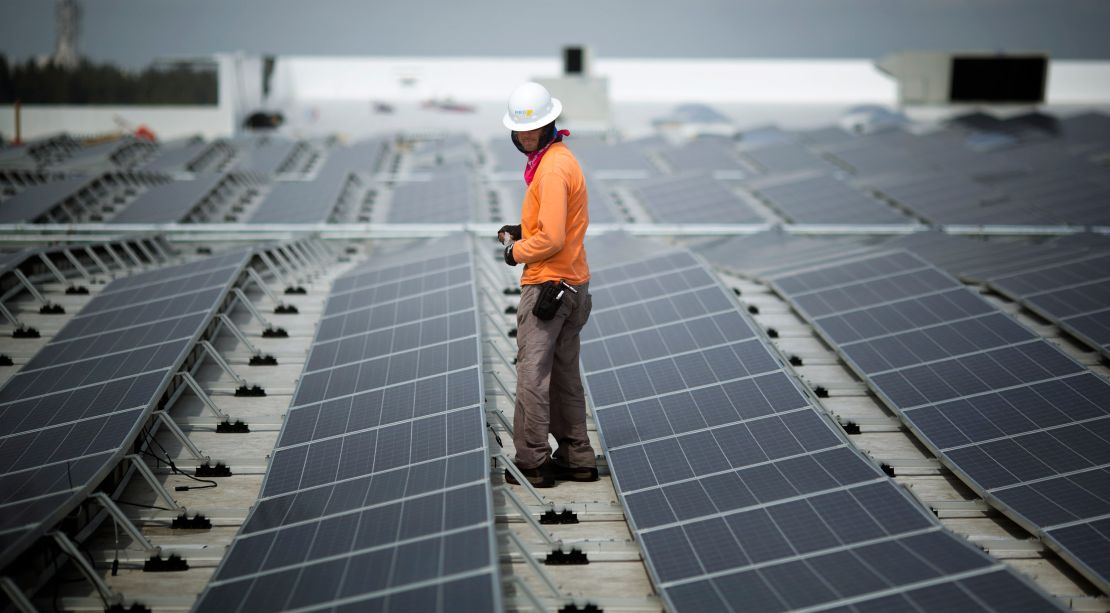 A worker walks among solar panels being installed on the roof of an IKEA in Miami in 2014. As of February, IKEA had solar installed at 90% of its US locations.