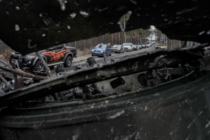 Cars drive past a destroyed Russian tank as civilians leave Irpin on March 9. A Ukrainian official said lines of vehicles <a href="index.php?page=&url=https%3A%2F%2Fwww.cnn.com%2Feurope%2Flive-news%2Fukraine-russia-putin-news-03-09-22%2Fh_9deca9c29779b4beb5c284e9a57f5f93" target="_blank">stretched for miles</a> as people tried to escape fighting in districts to the north and northwest of Kyiv.