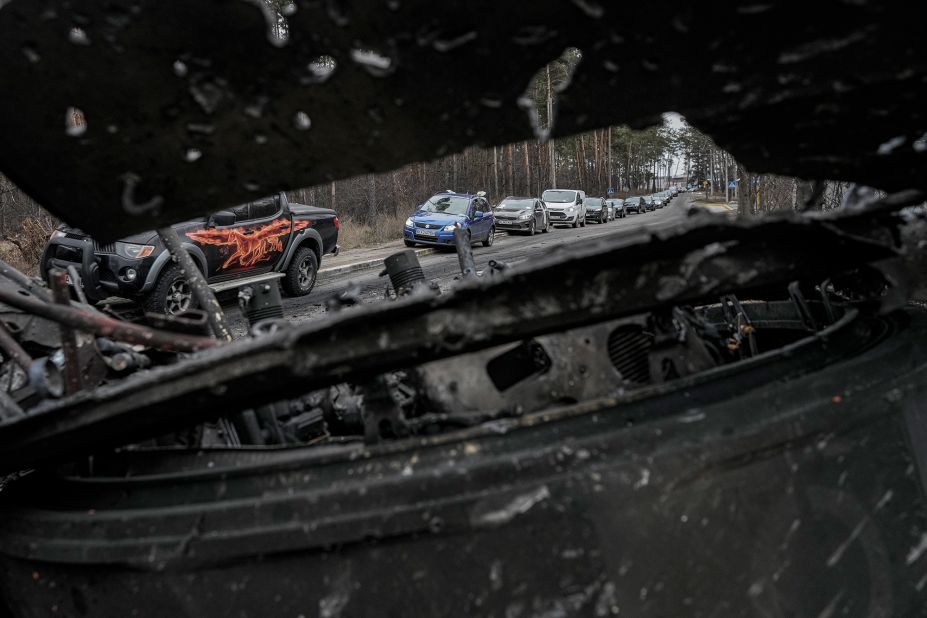 Cars drive past a destroyed Russian tank as civilians leave Irpin on March 9. A Ukrainian official said lines of vehicles <a href="https://www.cnn.com/europe/live-news/ukraine-russia-putin-news-03-09-22/h_9deca9c29779b4beb5c284e9a57f5f93" target="_blank">stretched for miles</a> as people tried to escape fighting in districts to the north and northwest of Kyiv.