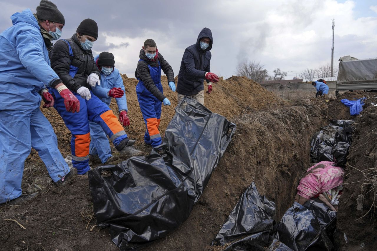 Dead bodies are placed into a mass grave on the outskirts of Mariupol on March 9. With overflowing morgues and repeated shelling, the city has been <a target=