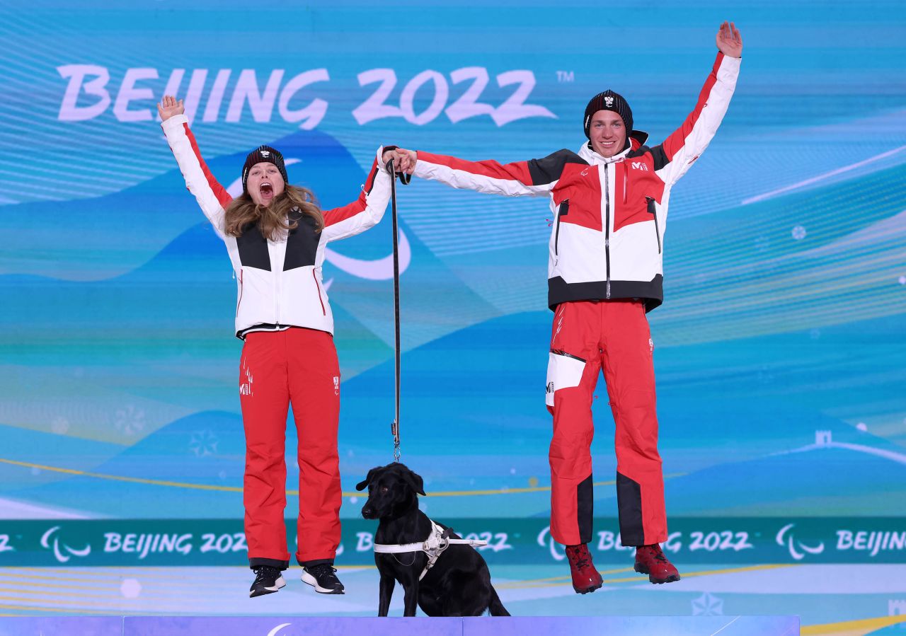 Austrian skier Carina Edlinger celebrates on the podium with her guide, Lorenz Josef Lampl, and her dog, Riley, after winning a gold medal on March 9.