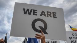 A woman shouts as she holds a placard reading "Q Army" (a reference to the Q-anon movement), during a protest against the measures to counter the coronavirus pandemic in the front of the Romanian Government headquarters August 10, 2020. - Hundreds of people, followers of conspiracies, declared supporters of US President Donald Trump asked the cease of what they called "Medical Dictatorship" about sanitary measures adopted by the Romanian government in the fight against the coronavirus pandemic. Protesters was shouting "No masks!" and "Freedom!". Despite the increasing numbers of casualties and infected people, a considerable part of Romanians still believe in a world-wide conspiracy about COVID-19. (Photo by Daniel MIHAILESCU / AFP) (Photo by DANIEL MIHAILESCU/AFP via Getty Images)