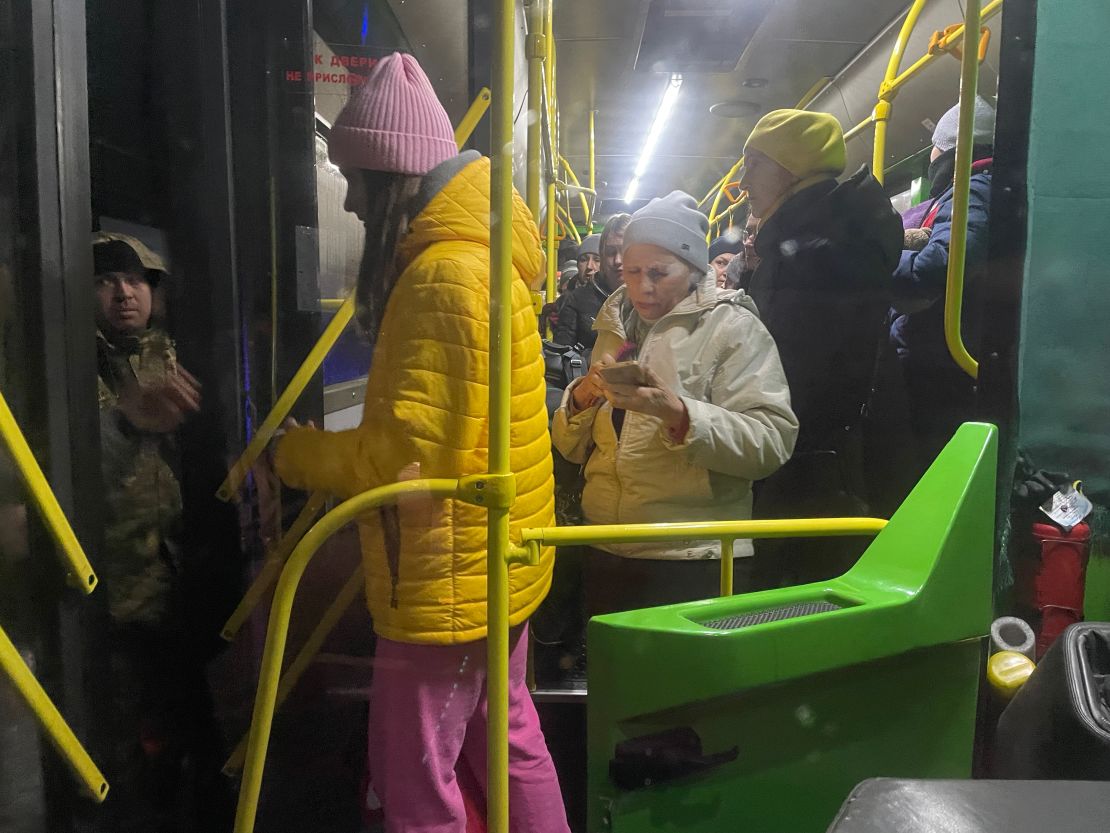 Refugees from Enerhordar alight the evacuation bus after document checks by Ukrainian soldiers.