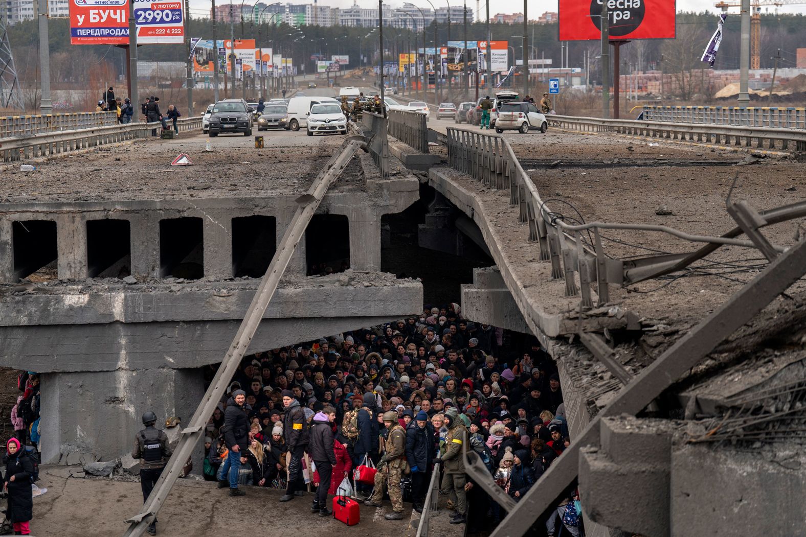 Ukrainians crowd under a destroyed bridge as they try to flee across the Irpin River on the outskirts of Kyiv, Ukraine, on Saturday, March 5.