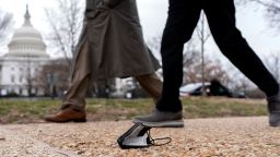 People walk past a protective face mask on the ground in Washington, DC, on March 1, 2022.