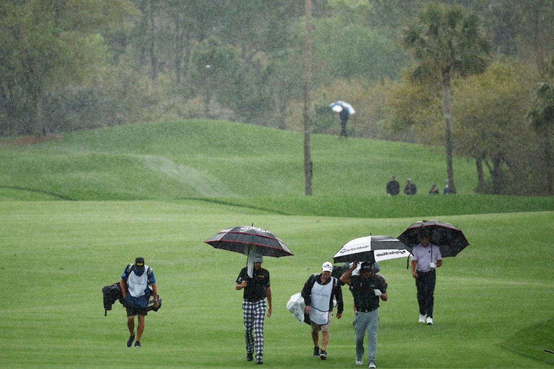 Poulter, Pat Perez and Jhonattan Vegas walk the fifth hole in the rain during the first round,