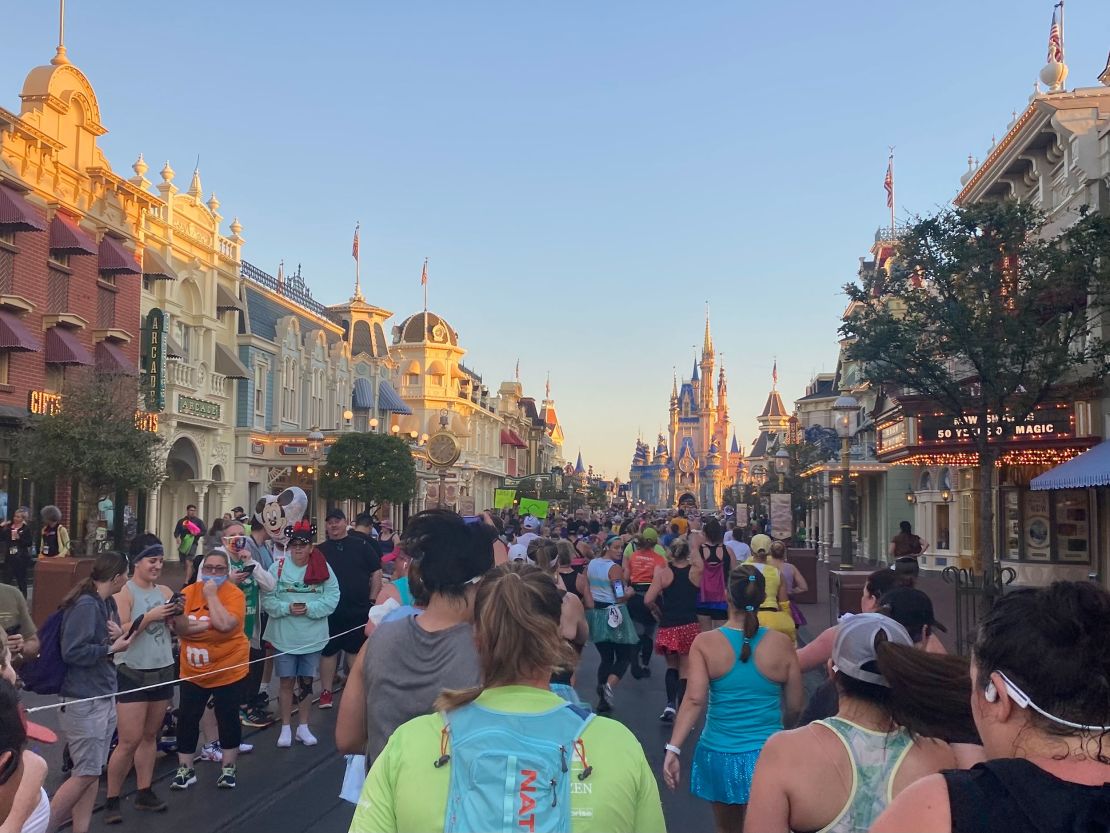 Princess Half Marathon racers head down Main Street at the Magic Kingdom, with Cinderella's Castle just beyond. 