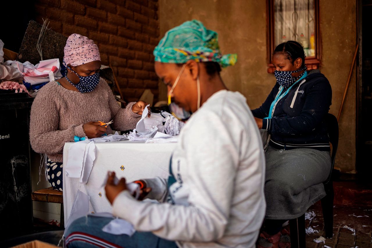 Women cut and sew cotton fabrics into pieces used to manufacture reusable face masks in Johannesburg's Alexandra township in April 2020. Worldwide, artisans and textile factories changed their practices to produce reusable face masks to help curb the spread of Covid-19.