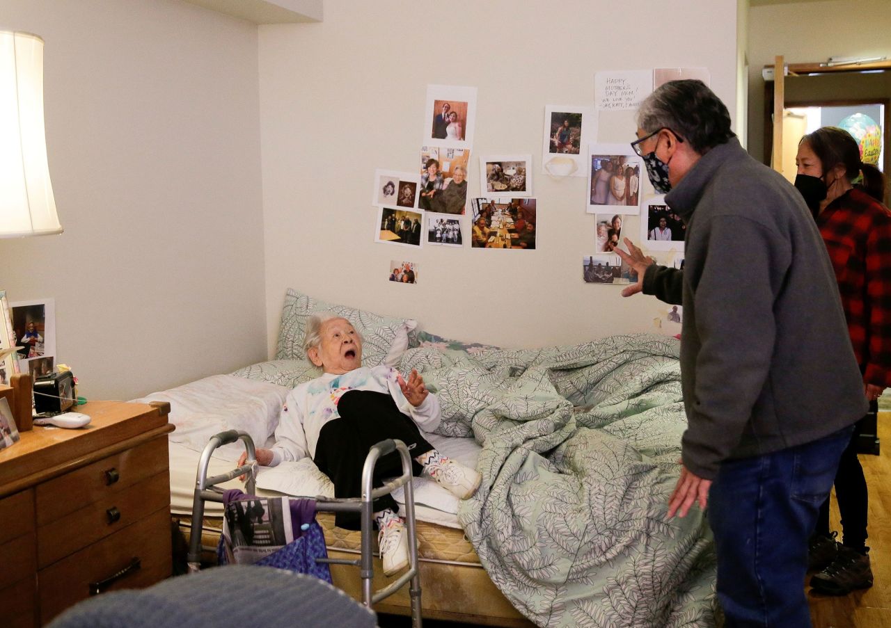 Yoshia Uomoto, 98, reacts as her son Mark Uomoto and niece Gail Yamada surprise her with their first in-person visit in a year after indoor visitation restrictions due to Covid-19 were lifted at an assisted living facility in Seattle in March 2021. Residents, who had been fully vaccinated, could visit with family for an hour at a time.<br />