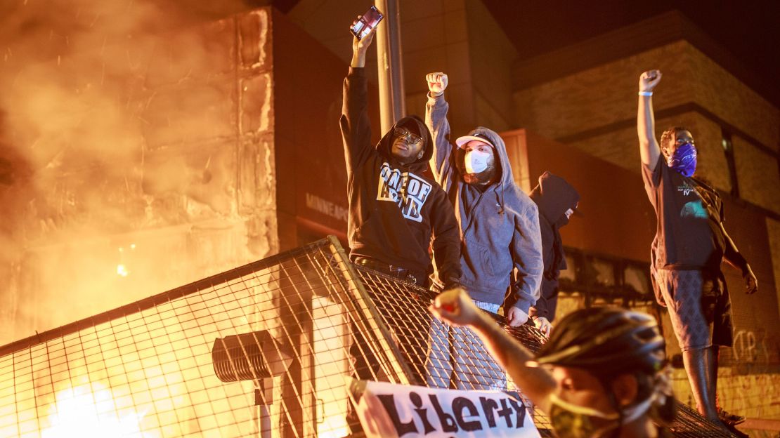 Protesters hold up their fists as flames rise behind them in front of the Third Police Precinct on May 28, 2020 in Minneapolis, Minnesota.