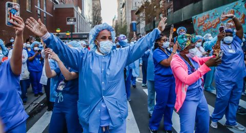 Health care workers wave back to people applauding them in New York in April 2020. To honor health care workers in the early months of the Covid-19 pandemic, New York residents would regularly cheer from their homes every evening. 