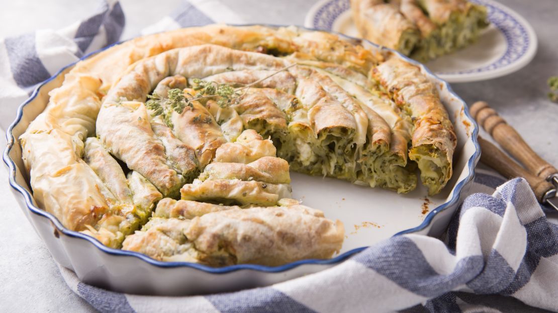 Greek pie spanakopita  over concrete  background. Ideas and recipes for vegetarian or vegan  Spinach Pie from fillo pastry cut in slices. Copy space. Top view or flat lay.