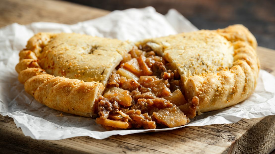 Cornouailles traditionnelles remplies de viande de boeuf, de pommes de terre et de légumes dans l'assiette noire.