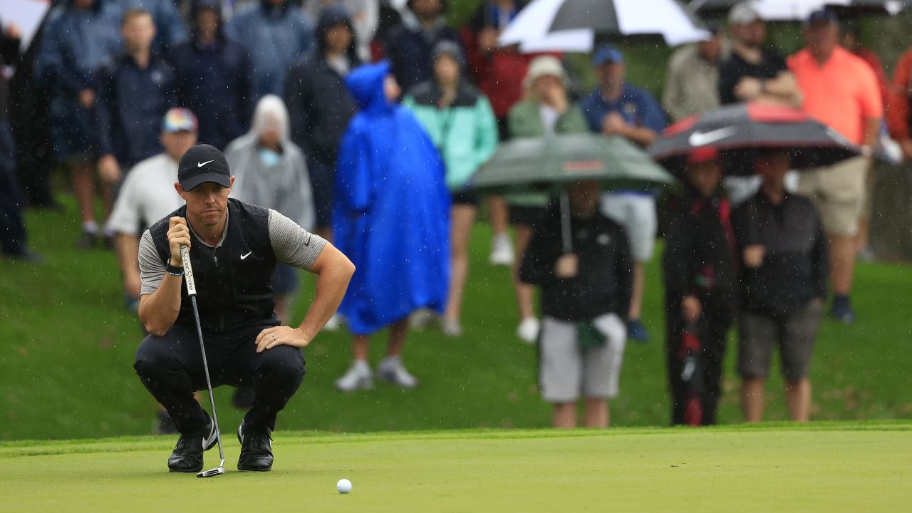 Rory McIlroy of Northern Ireland lines up his putt amid the rain.